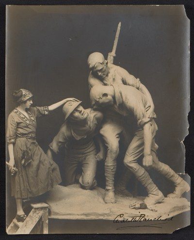 Sculptor Gertrude Vanderbilt Whitney Woman in early 20th-century attire interacting with war sculpture of two soldiers.