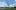 Abstract metallic tree sculpture on grass, modern building in background, cloudy sky above.