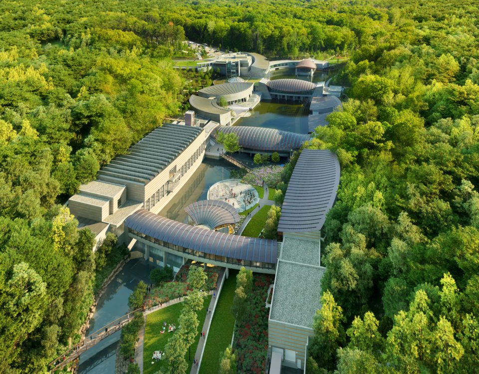 Aerial rendering of Crystal Bridges expansion Modern architectural complex with curved roofs in a lush forested area, connected by pathways.