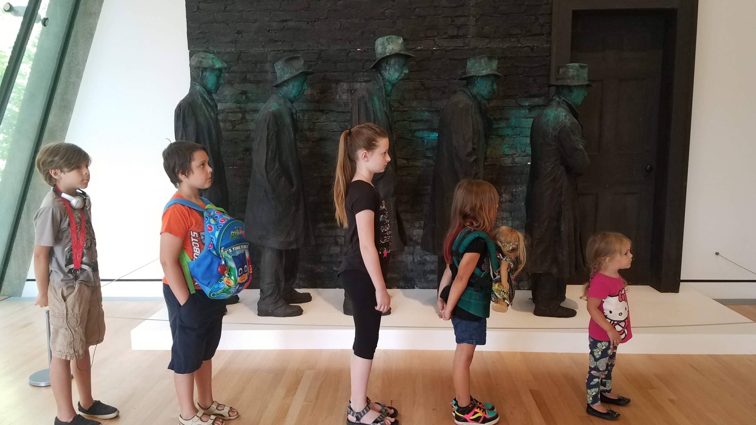 Astrid Turner five children visitors pose in front of depression bread line in the galleries