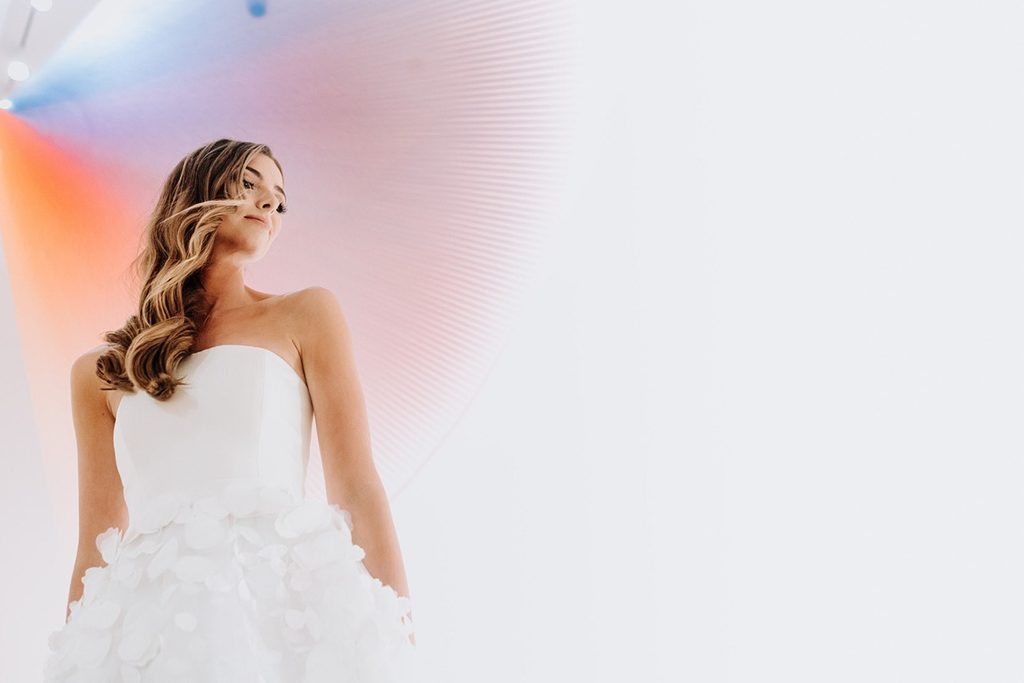 Wedding Venue Woman in strapless white dress with wavy hair, colorful lighting, light background.