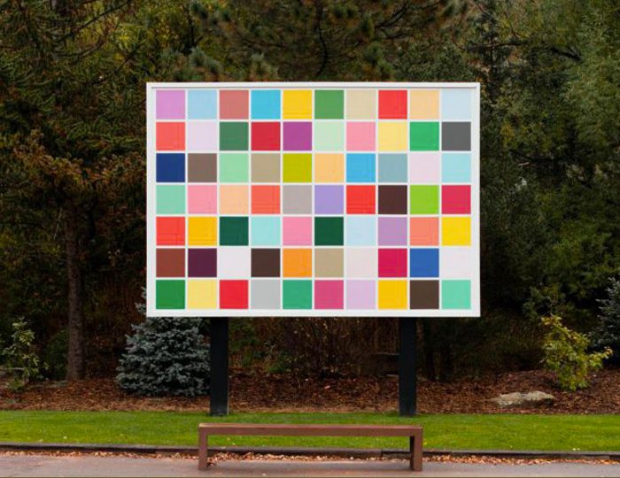 Spencer Finch, Back to Kansas, 2015, 130 x 186 in. (bottom of artwork is 60 inches from the ground), Collection of Christian Keesee, New York and Oklahoma Outdoor sign with colorful squares in park setting, trees and bench in front.