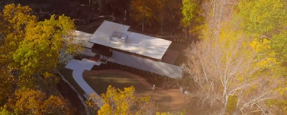 Frank Lloyd Wright Bachman-Wilson House overhead view Modern flat-roofed house in autumn trees, white walkway, landscaped areas, aerial view.