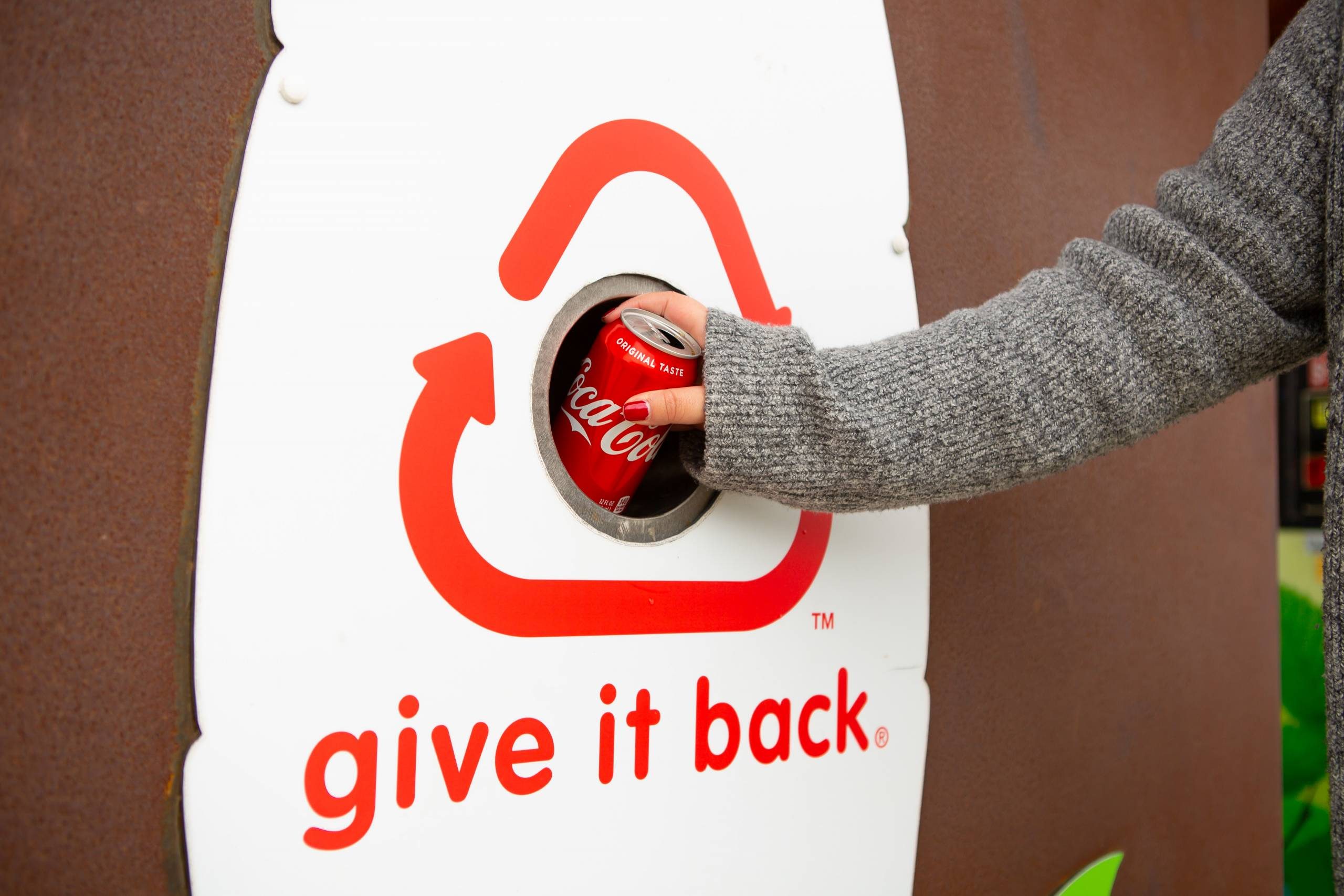 Recycling Bin A person recycling a Coca-Cola can in a bin labeled