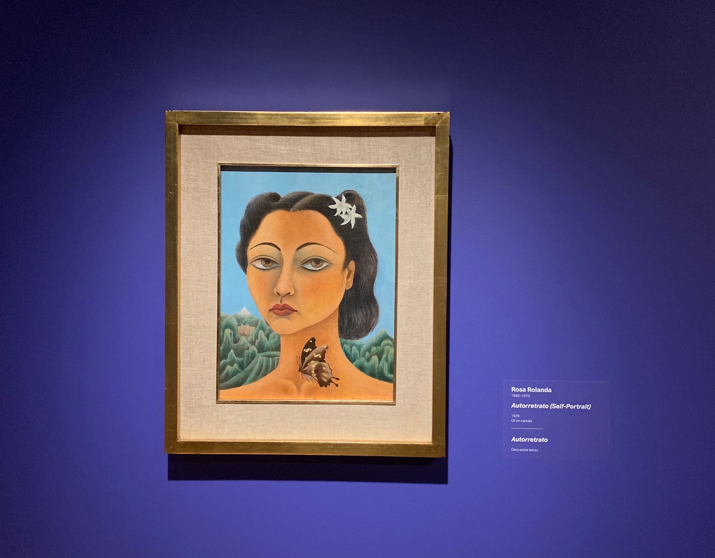Rosa Rolanda, Autorretratro (Self-Portrait), 1939, oil on canvas, 15 3/4 × 11 3/4 in. Crystal Bridges Museum of American Art, Bentonville, Arkansas, 2021.4. Portrait of woman hanging on gallery wall with label beside it