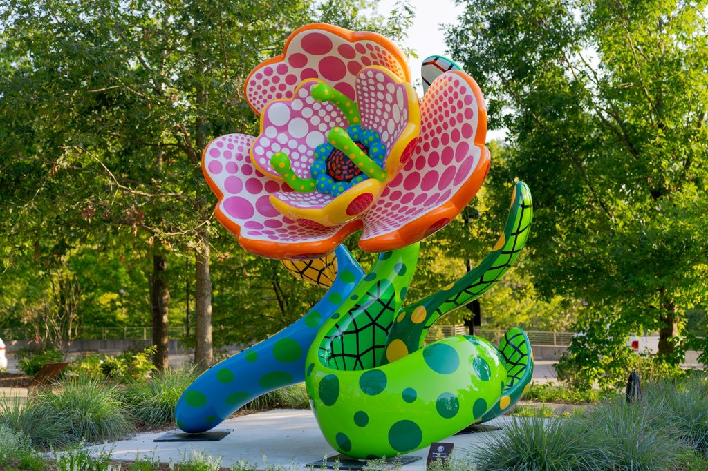 A large, colorful flower made of painted steel posed like a rearing snake on Orchard Trail at Crystal Bridges.