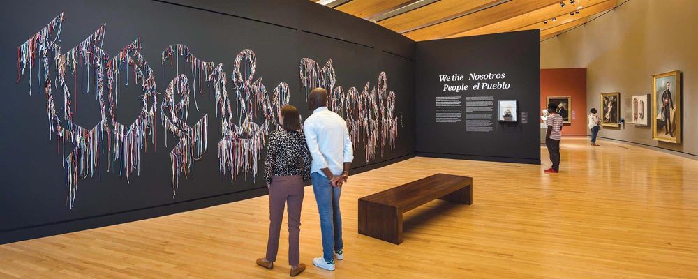 Visitantes en las galerías enfrente de la obra Nosotros el pueblo