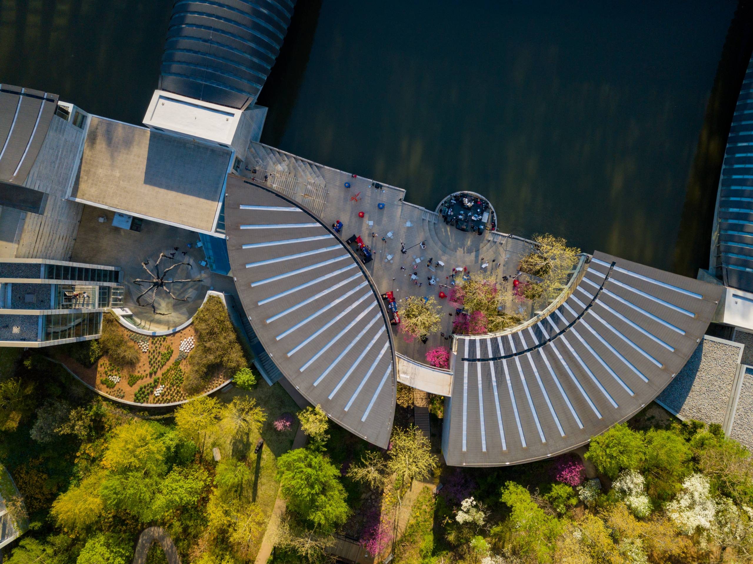 Aerial view of Walker Landing Aerial view of modern complex with curved roofs, gardens, and seating near water.