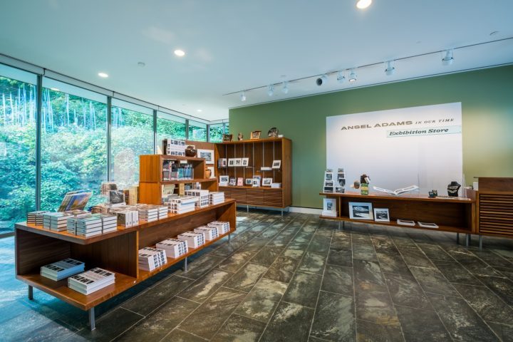 Ansel Adams: In Our Time Exhibition Store Exhibition store with books and photos, large windows, greenery, stone floor, Ansel Adams signage.