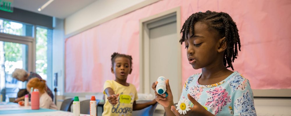 Children Crafting in Bright Room Children crafting in a bright room with glue, daisy, and colorful bottles on the table.