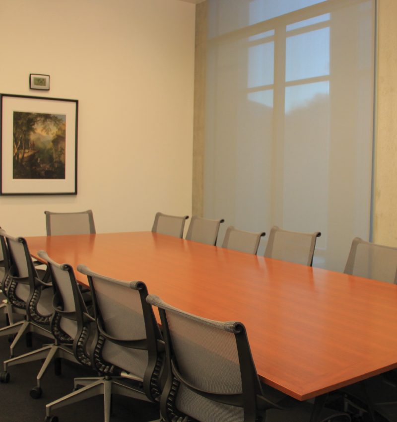 Meeting Space Conference room with wooden table, ten mesh chairs, large window, and framed artwork on wall.