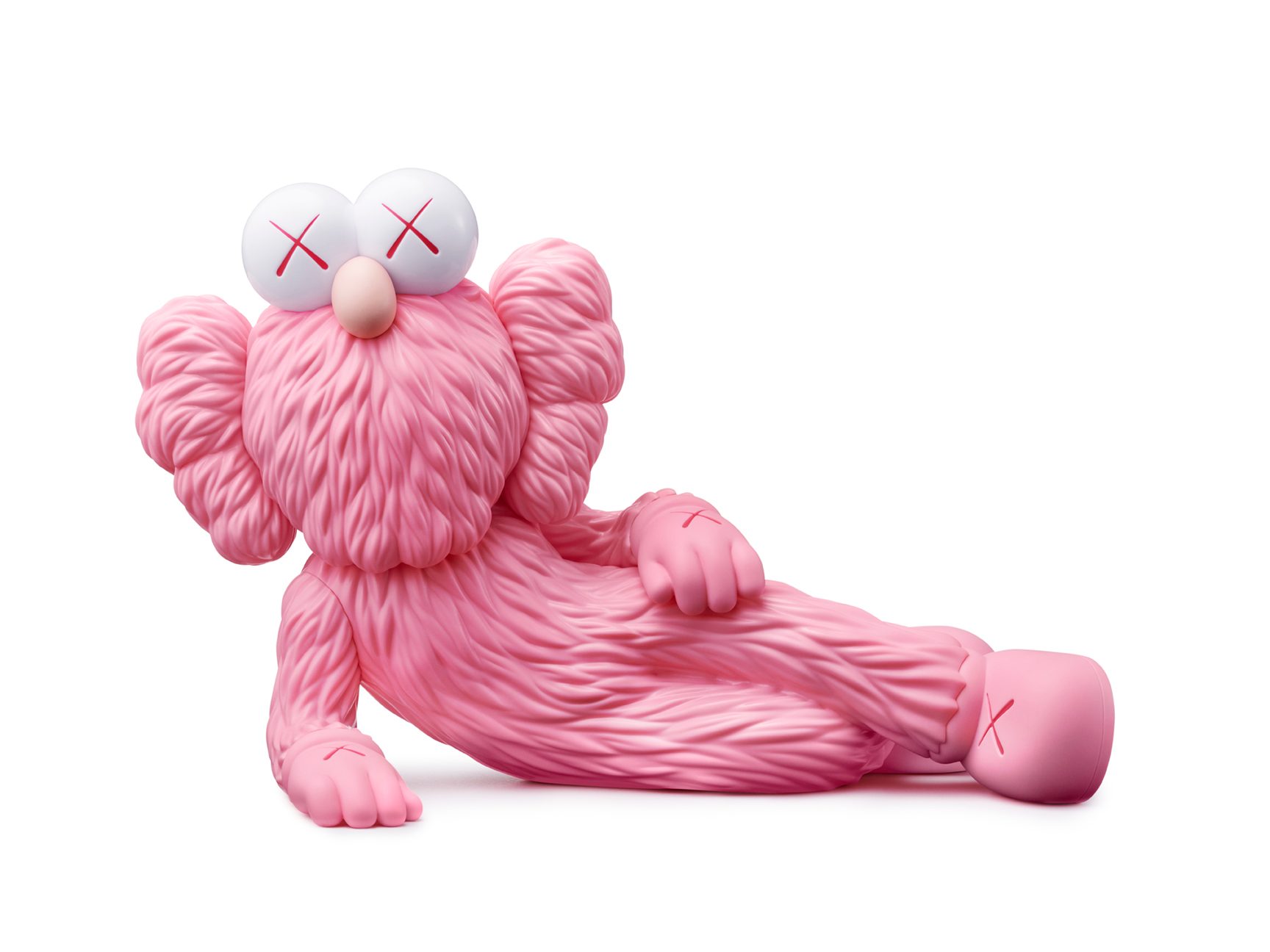 KAWS, TIME OFF, 2023. Vinyl, paint, 7 in. x 11 in. x 5 9/10 in. © KAWS. Photo: Brad Bridger A pink sculpture of a figure laying down in the style of the artist KAWS.