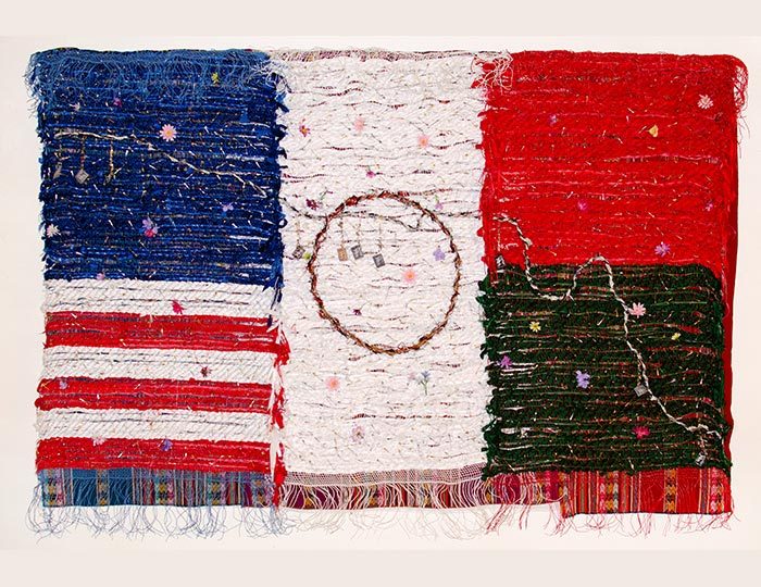 Consuelo Jimenez Underwood, Home of the Brave, 2013, wire, silk, fabric, safety pins, and synthetic and natural threads, 71 x 103 1/2 in. Courtesy of the artist Woven artwork blending American and Mexican flags with stars, stripes, and colored bands.