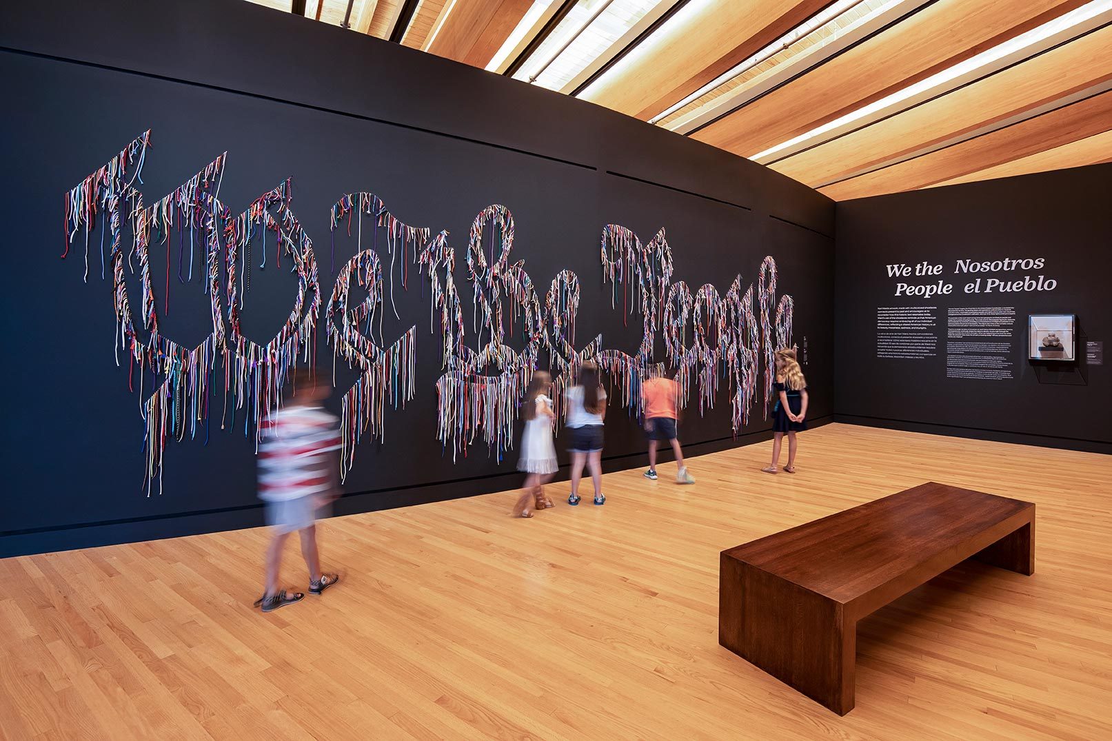 Children viewing Nari Ward We the People (black version), 2015, Shoelaces, 8 ft. × 27ft. Crystal Bridges Museum of American Art, Bentonville, Arkansas. Children viewing the artwork We the People